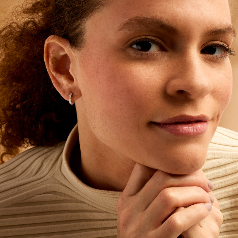 Diamond huggie hoop earrings in sterling silver on model's ear
