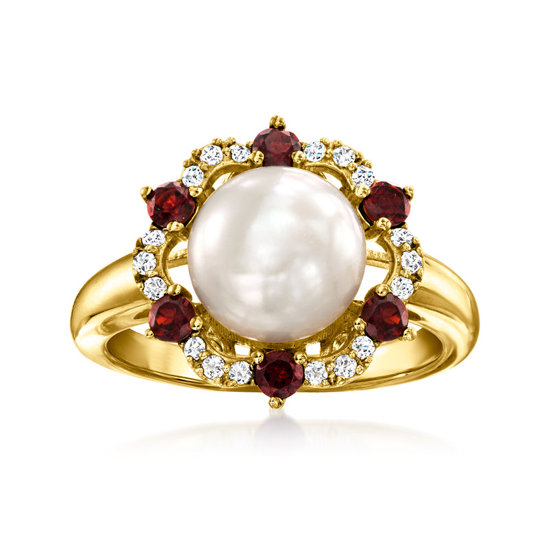 Gold-tone ring with large white pearl center, red garnet accents, and clear stone halo.