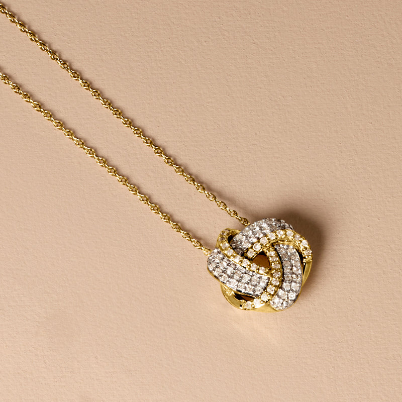 Gold love knot diamond pendant necklace close-up with detailed stones