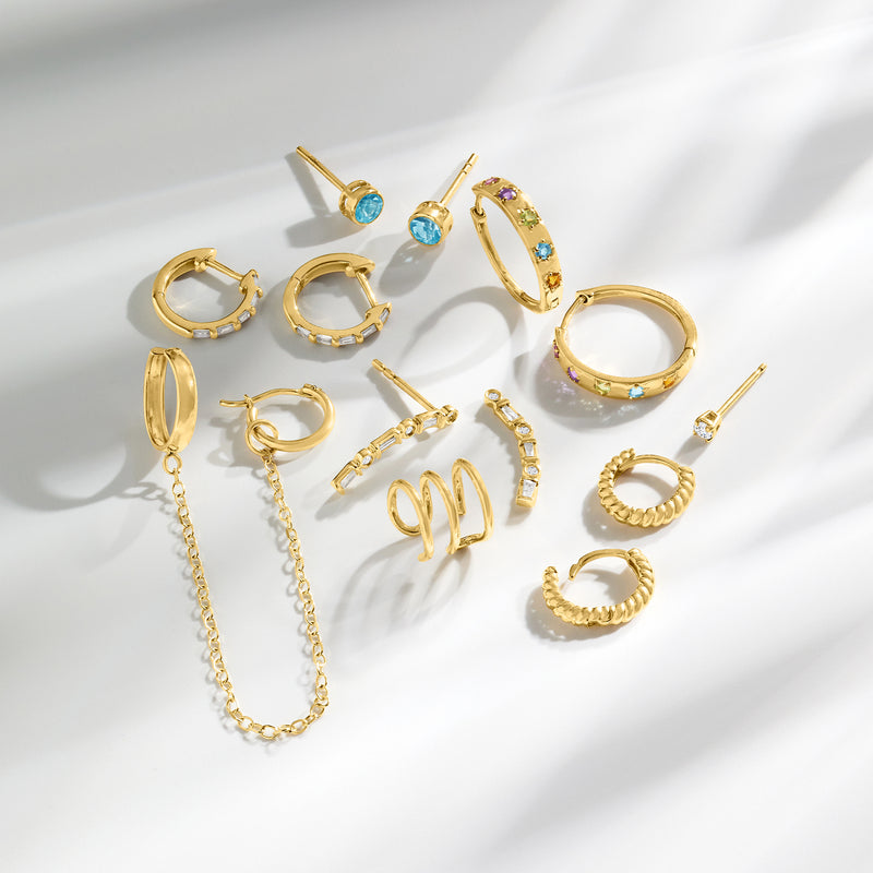 Gold huggie hoop earrings with diamond accents, shown among other earrings