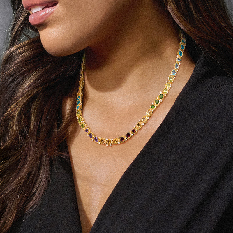 Gold multi-gemstone necklace with small bezel-set blue, green, purple, and yellow stones