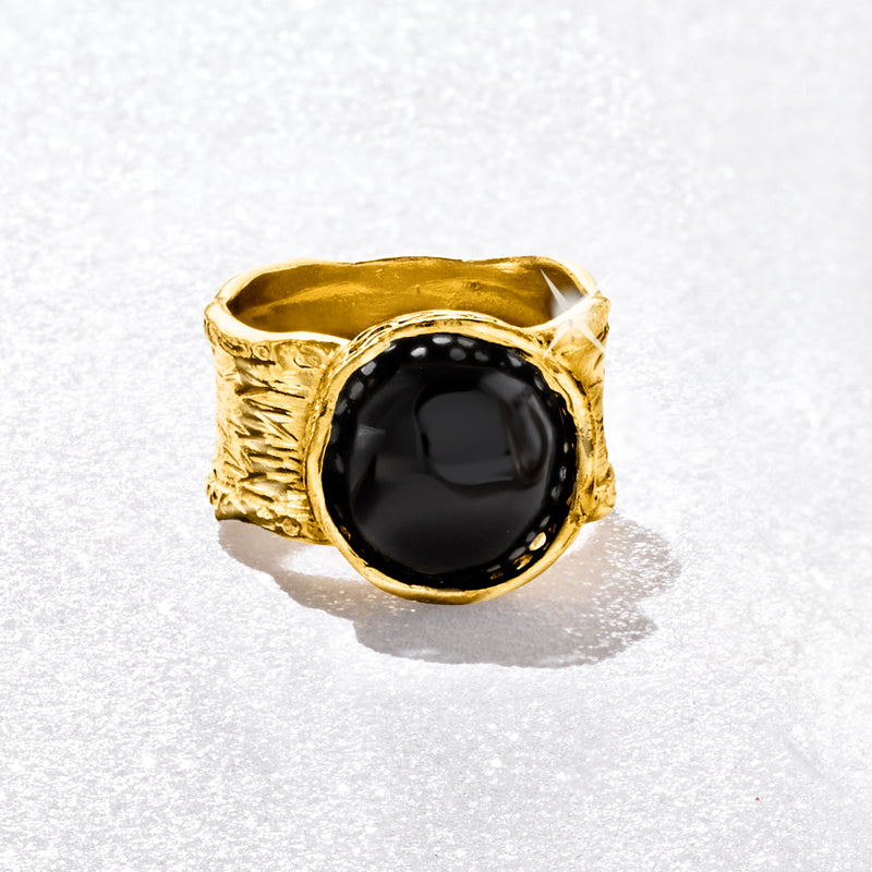 Wide gold-tone ring with round black onyx cabochon in hammered, sculpted band