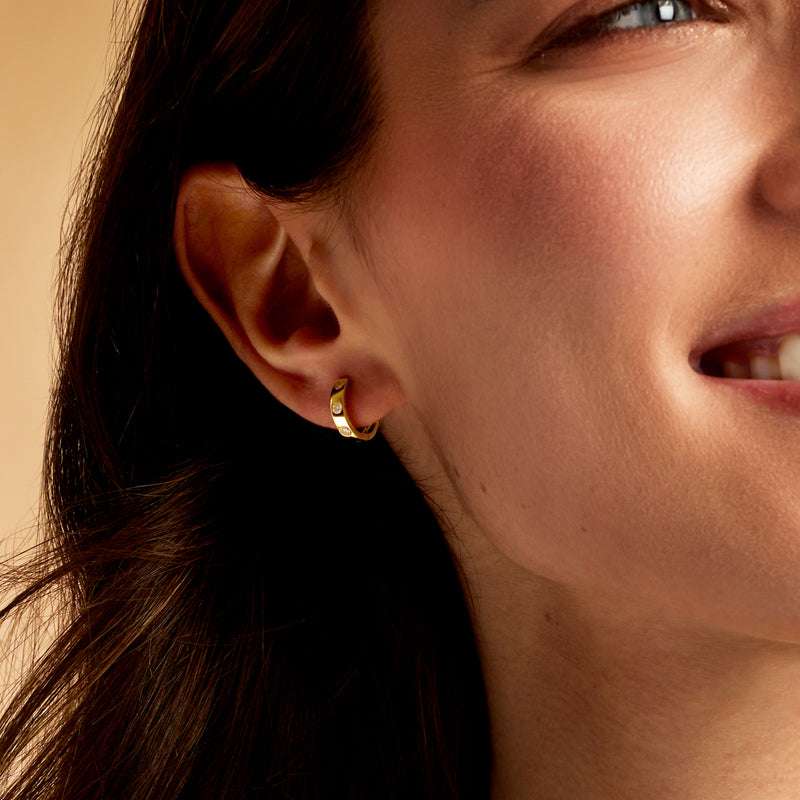 Small 14kt yellow gold huggie hoop earring with round bezel-set diamonds