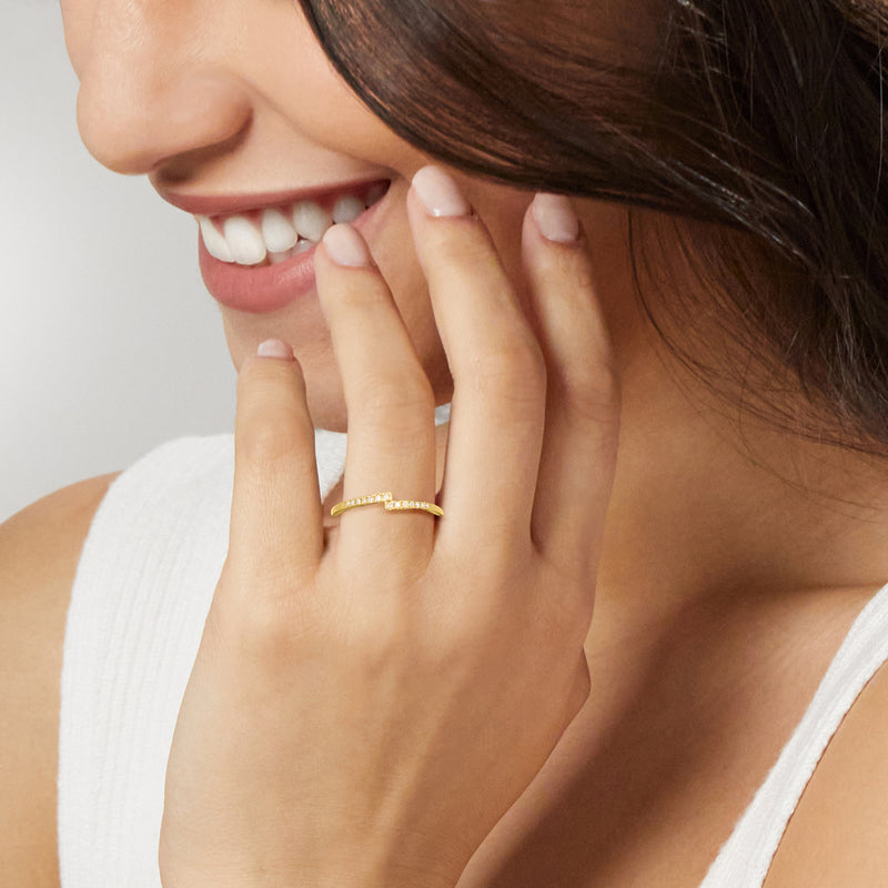 Diamond linear band ring in yellow gold on finger, small bright stones along top