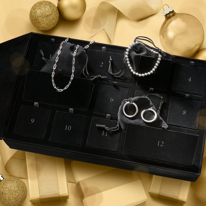 Silver-toned fine jewelry gift set with necklace, hoop earrings, bracelet, and rings in tray