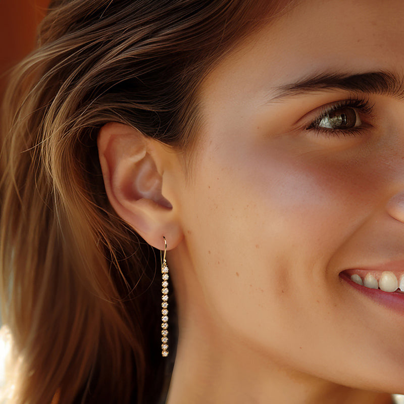 14kt yellow gold linear diamond drop earrings shown on ear, row of round stones