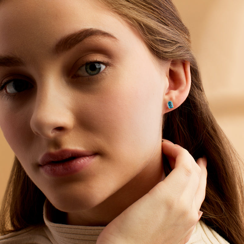 Blue topaz stud earrings in 14kt yellow gold on ear, rectangular stones
