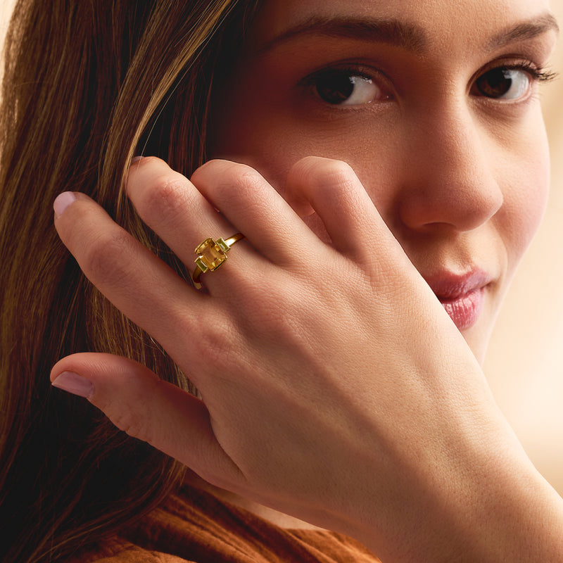 Gold ring with rectangular citrine and green peridot stones, worn on finger