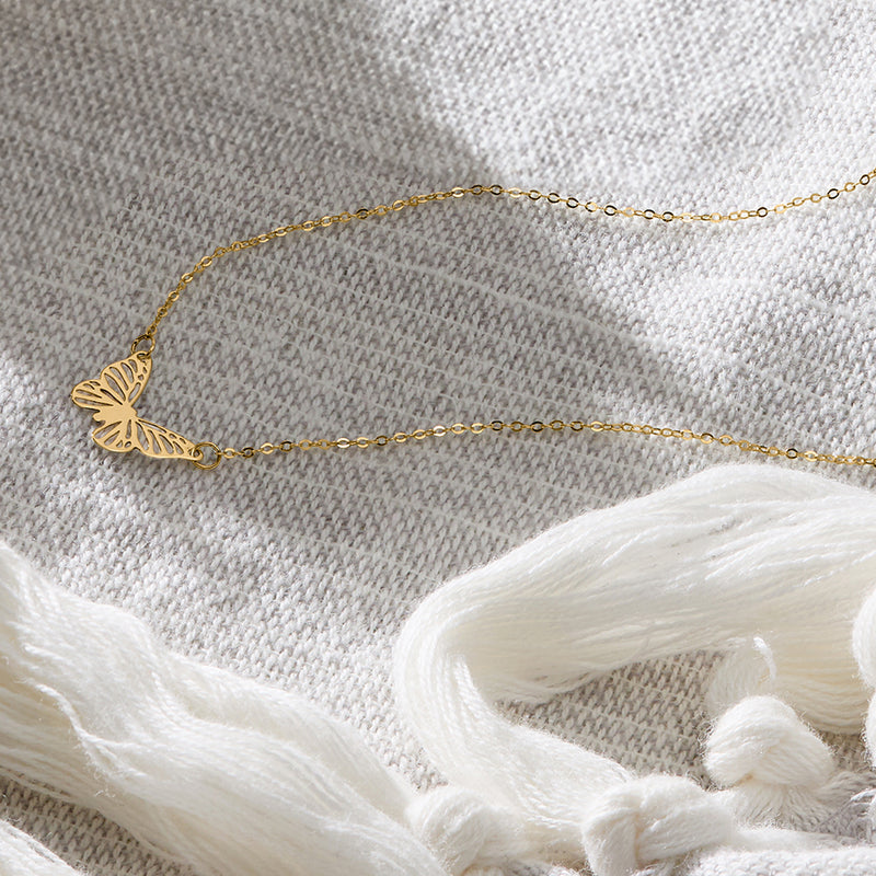 Yellow gold butterfly pendant necklace with chain laid flat