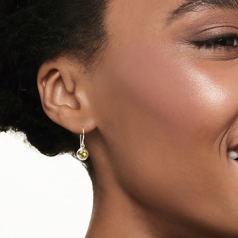 Sterling silver peridot drop earrings on ear, green round stone in bezel