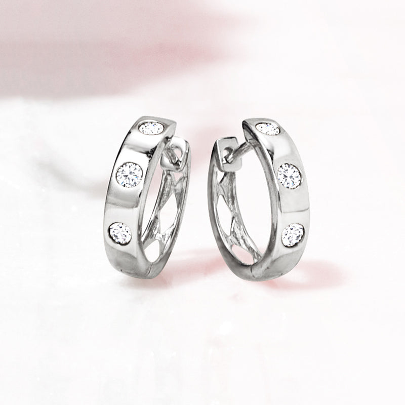 Sterling silver huggie hoop earrings showing round diamond stones on the front