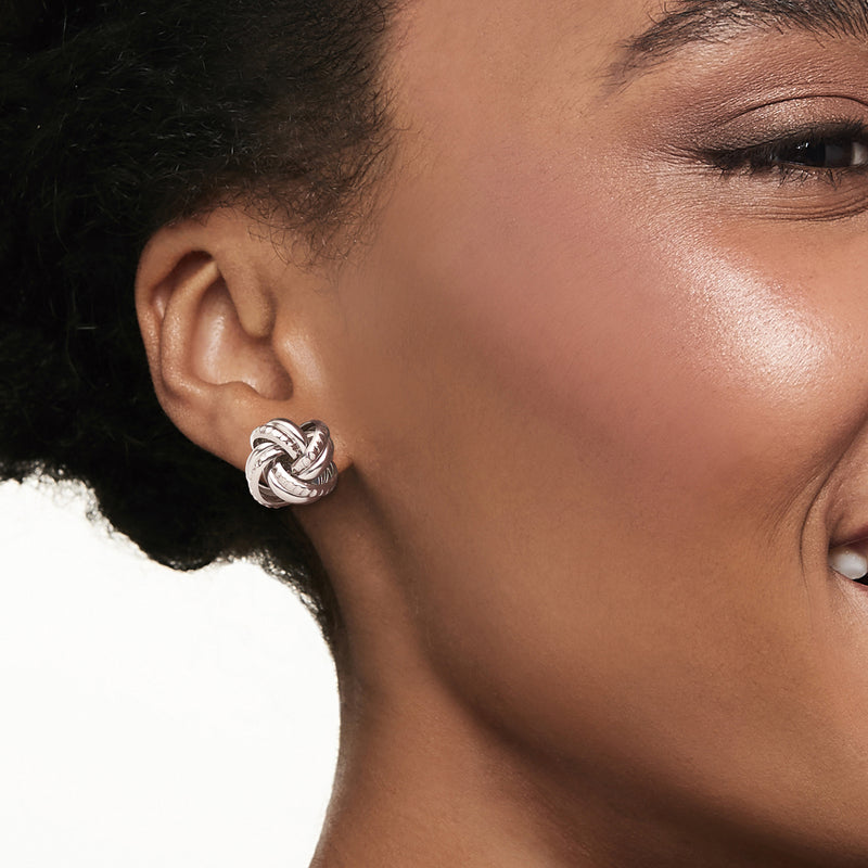 Sterling silver love-knot stud earring on model ear, small interwoven knot