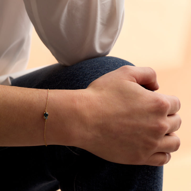 14kt yellow gold bracelet with blue topaz gemstone on wrist, slim chain