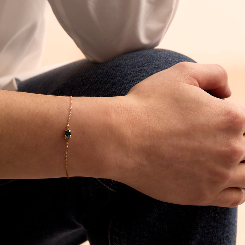 14kt yellow gold bracelet with blue topaz drop on wrist, thin link chain