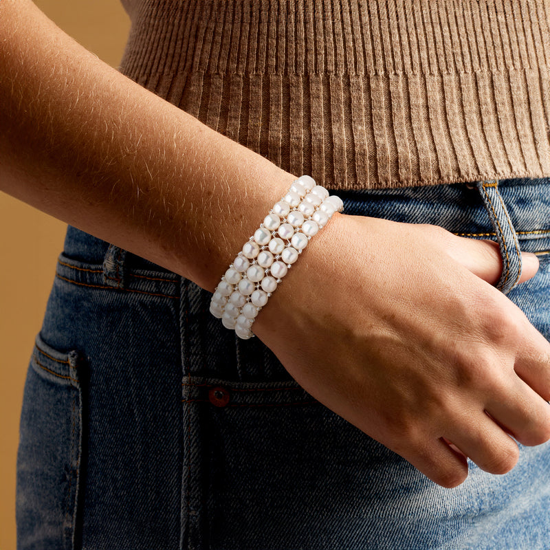 Worn three-row cultured pearl bracelet with 6–7mm round white pearls on wrist