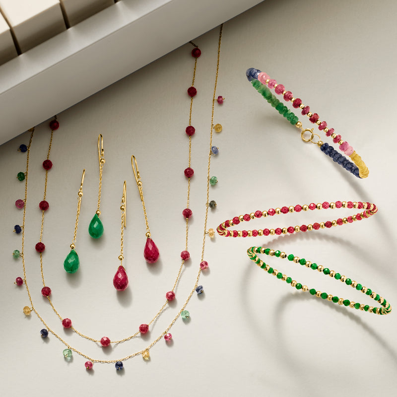 Ruby bead station necklace with gold chain and round red beads among other jewelry.