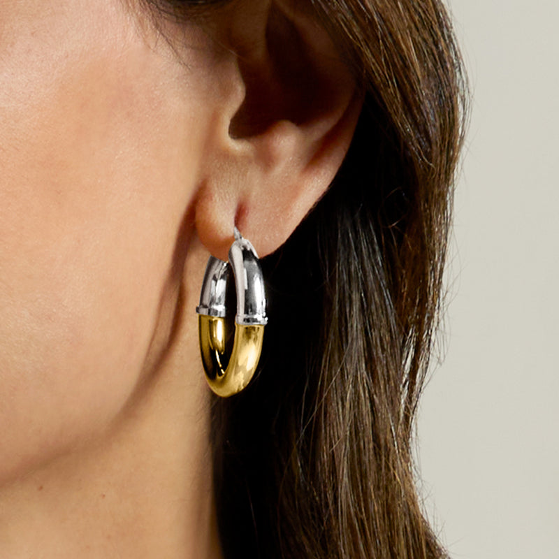 Two-tone hoop earrings on ear: polished silver and gold with hinged closure