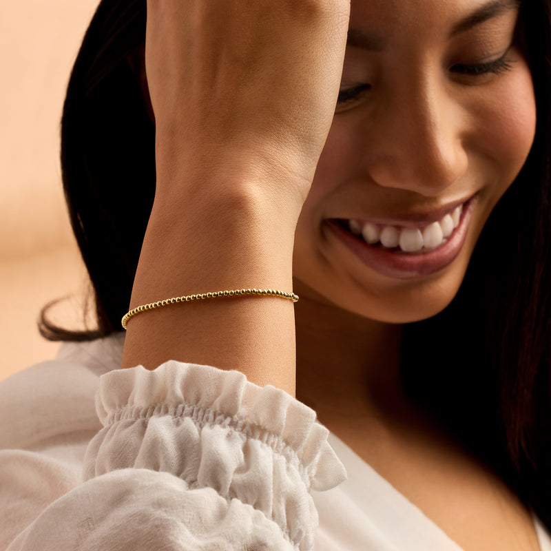 Yellow gold beaded bracelet on wrist with hinged clasp