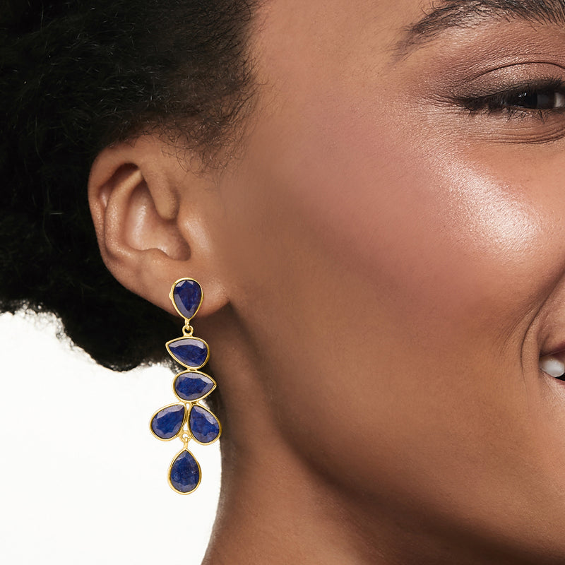 Sapphire drop earrings on model ear: gold-tone hoops with four dark blue teardrop stones