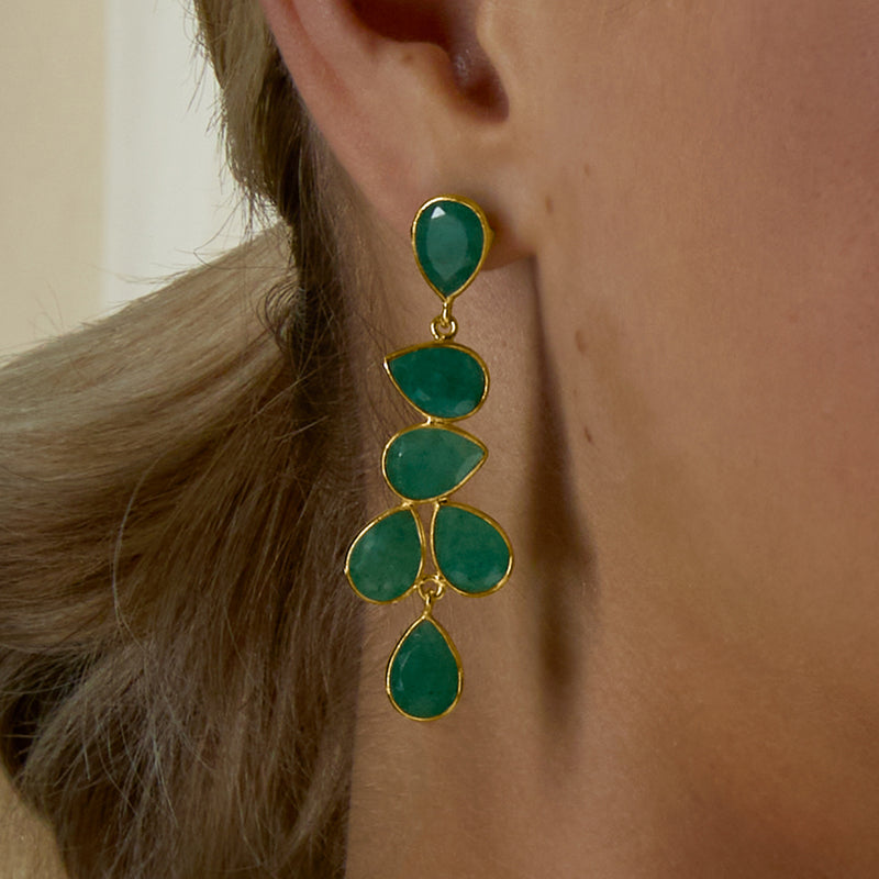 Emerald drop earrings worn on ear, green teardrop stones in gold over sterling setting