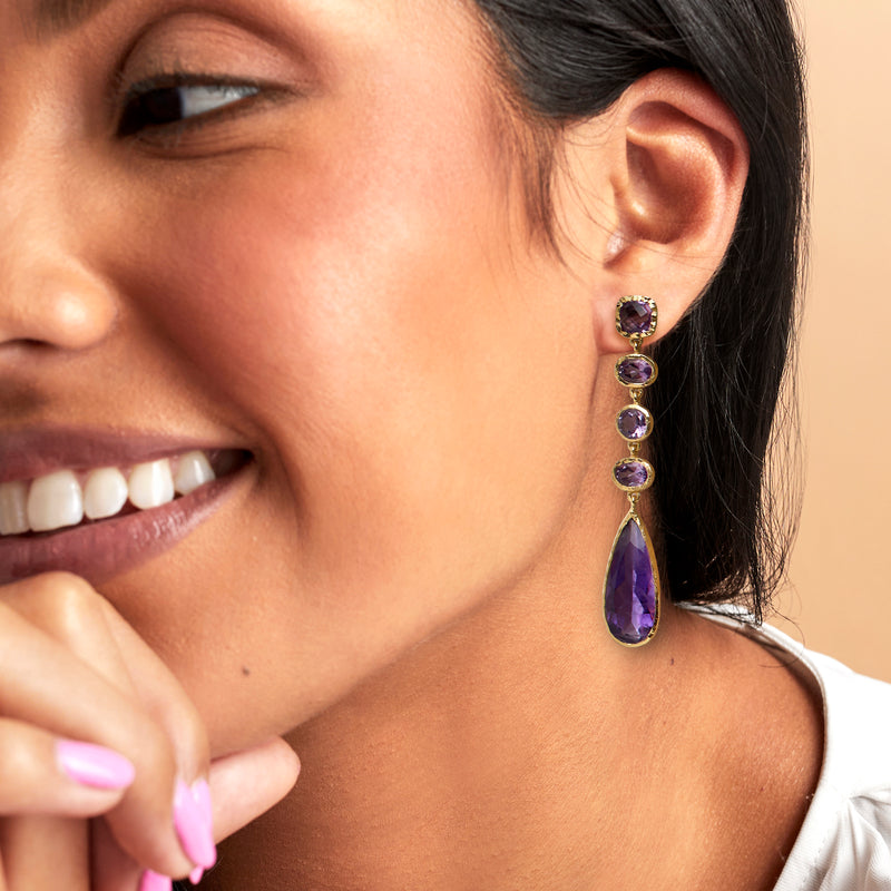 Amethyst drop earrings on model, gold-tone with purple round stones and long teardrop