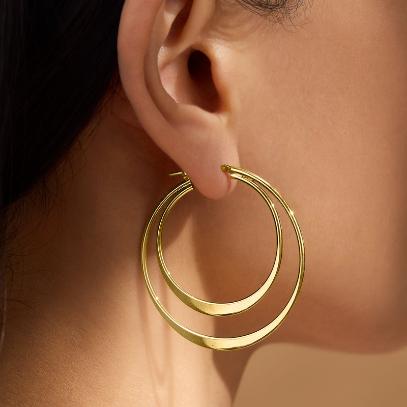Gold-tone double hoop earrings on ear, smooth layered rings