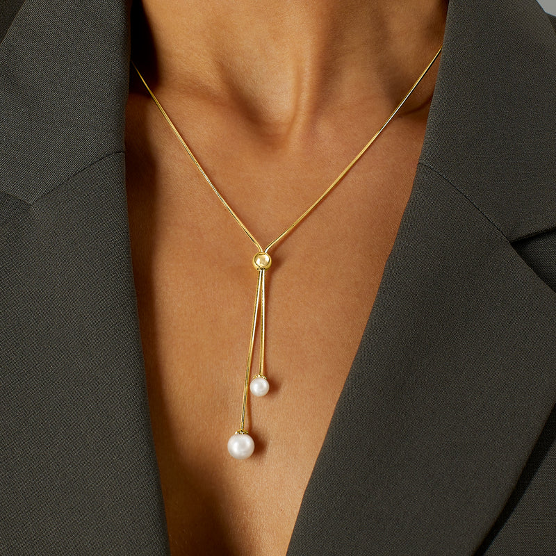 Gold lariat necklace with two dangling white cultured pearls and round clasp bead