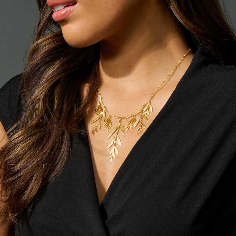 Gold leaf branch necklace with dangling leaf charms along a thin collar chain