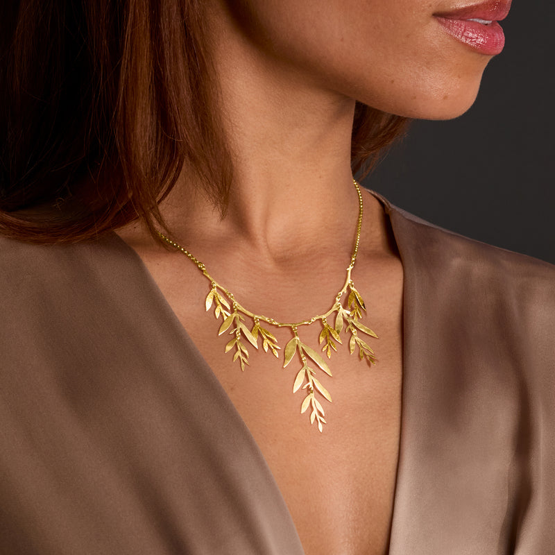 Gold leaf branch collar necklace with dangling leaf charms in a V-shaped design