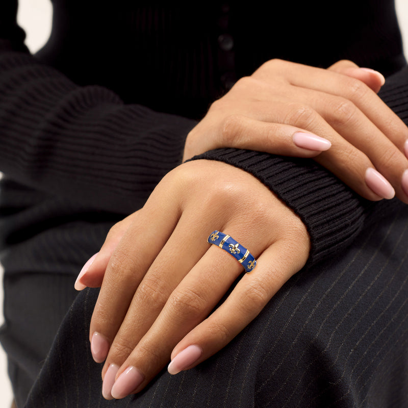 Blue enamel fleur-de-lis ring on hand with gold-tone band and glossy blue panels