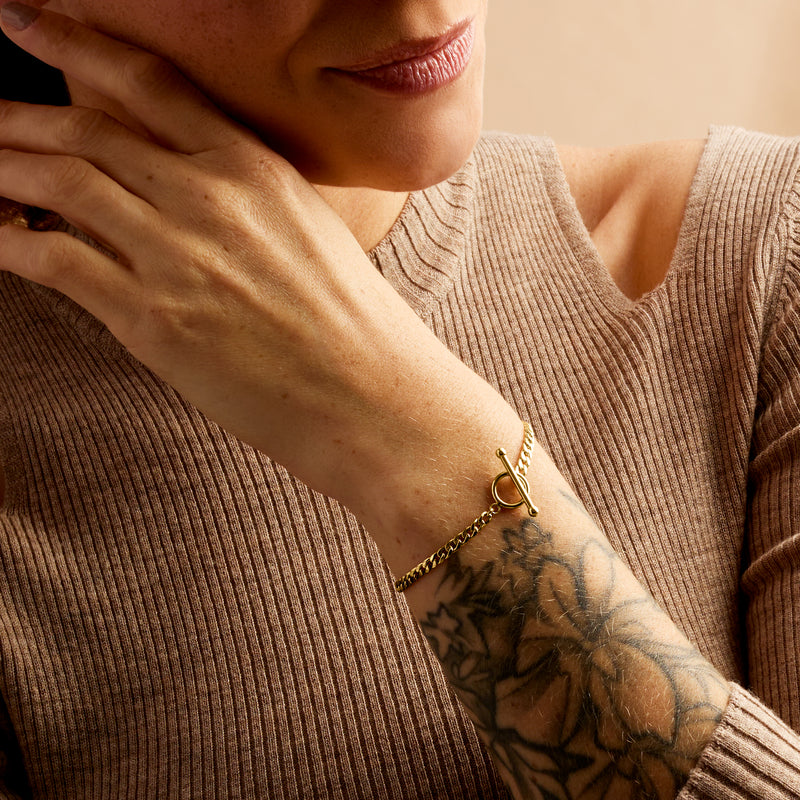 Yellow gold curb-link bracelet with toggle clasp worn on wrist