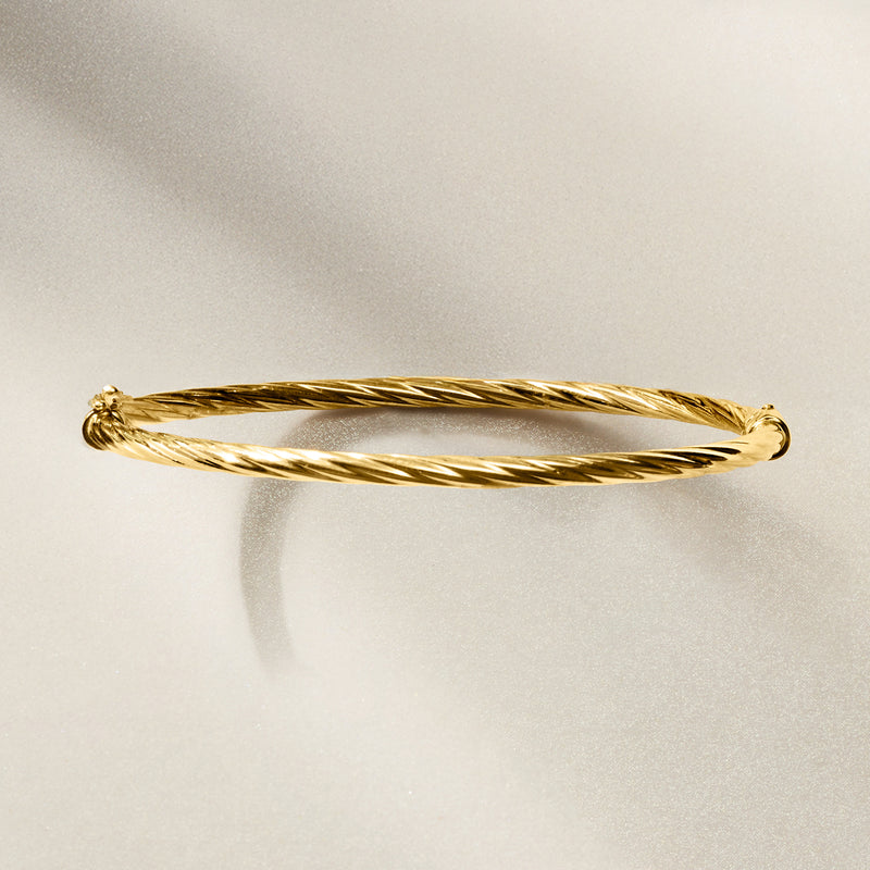 Twisted yellow gold bangle bracelet with braided rope texture and end knot detail