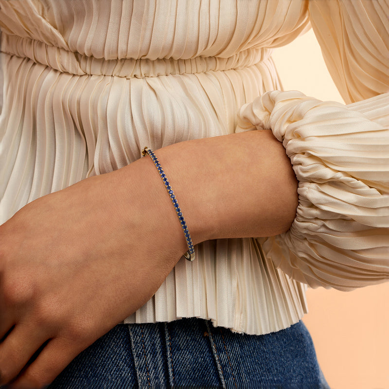 Blue sapphire bangle on wrist in 18kt gold over sterling