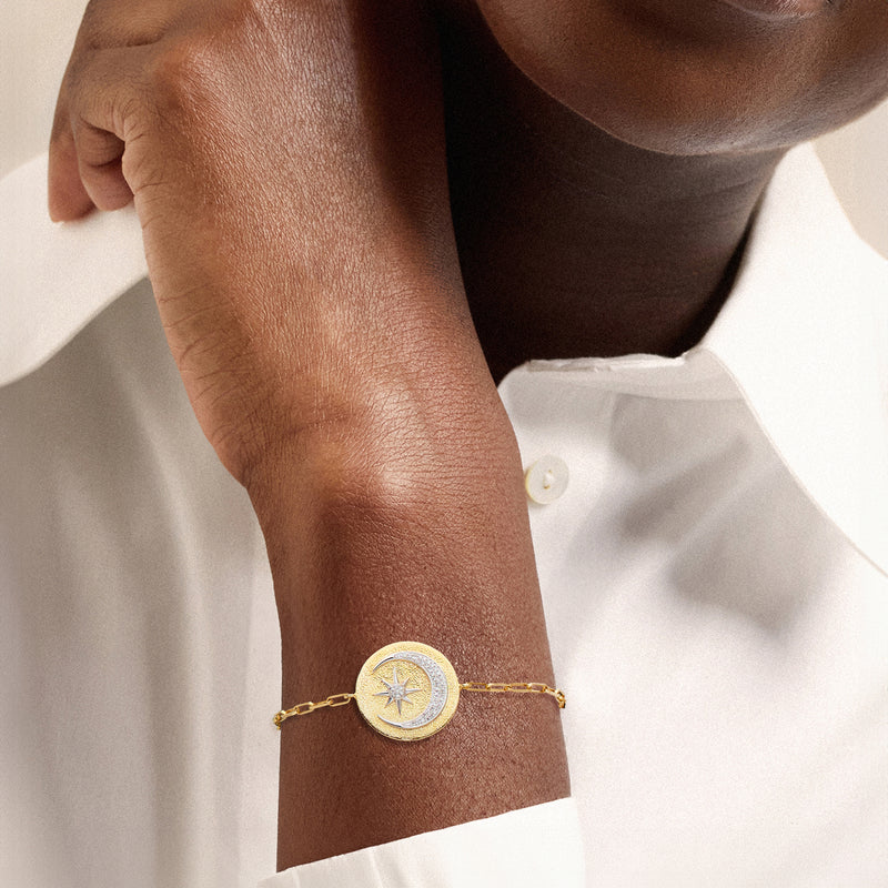 Gold link bracelet with small round moon-and-star charm on wrist