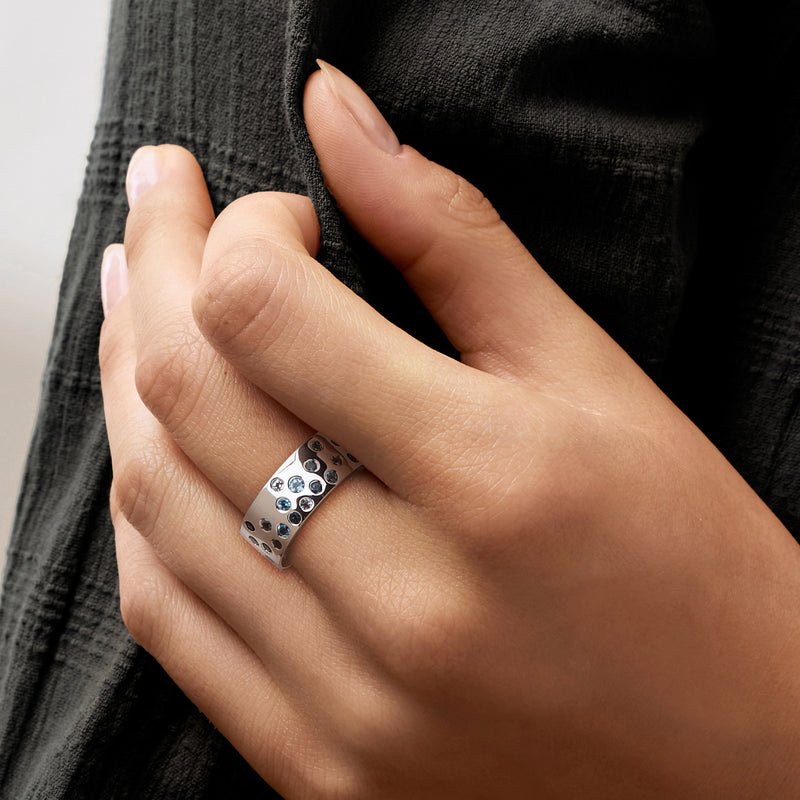 Sterling silver ring with blue topaz and clear round stones on finger