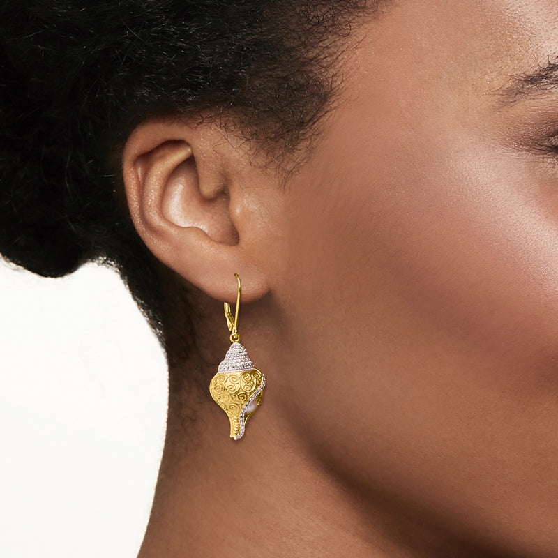 Gold leverback drop earrings on model, textured swirl dangle with white gemstone cap