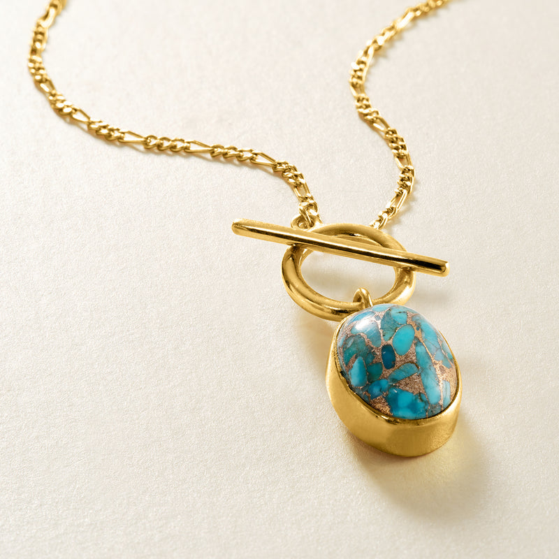 Gold toggle necklace detail: cross bar and oval turquoise stone charm