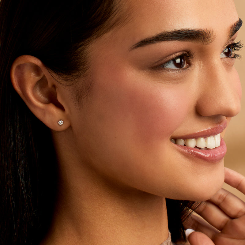 Round diamond stud earrings on ear, sterling silver bezel settings
