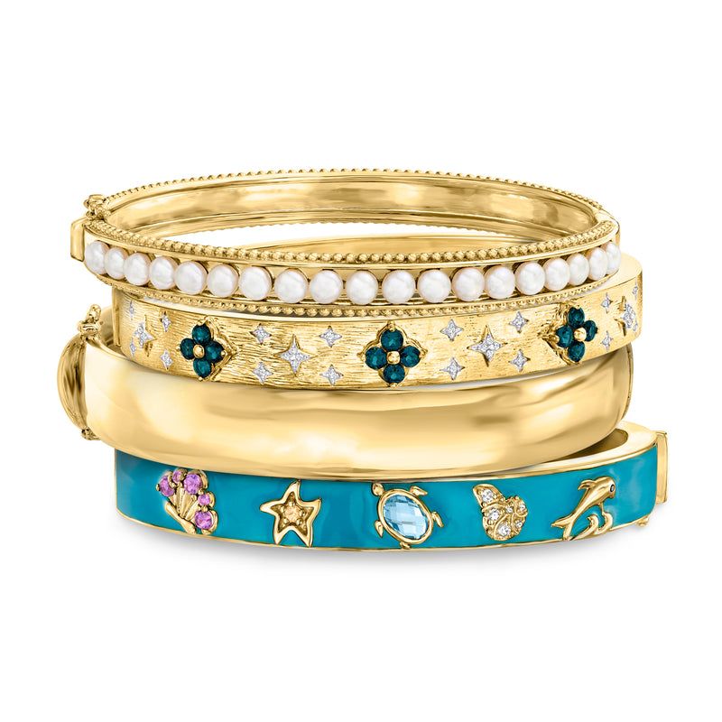 Set of four gold bangles with blue enamel, star charms, and gemstone accents