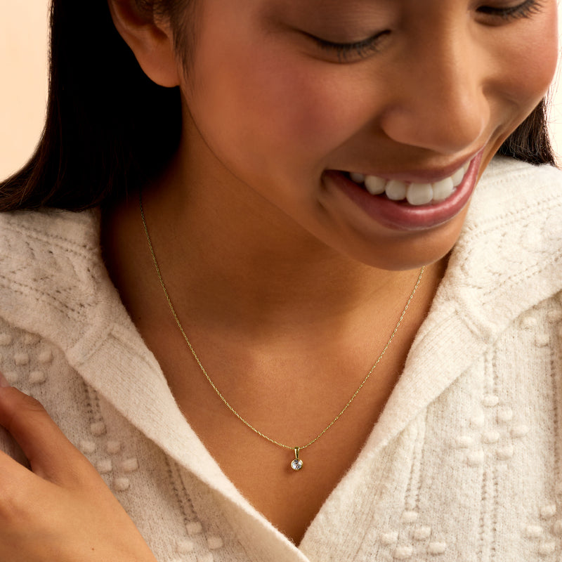 Delicate yellow gold necklace with small round aquamarine pendant