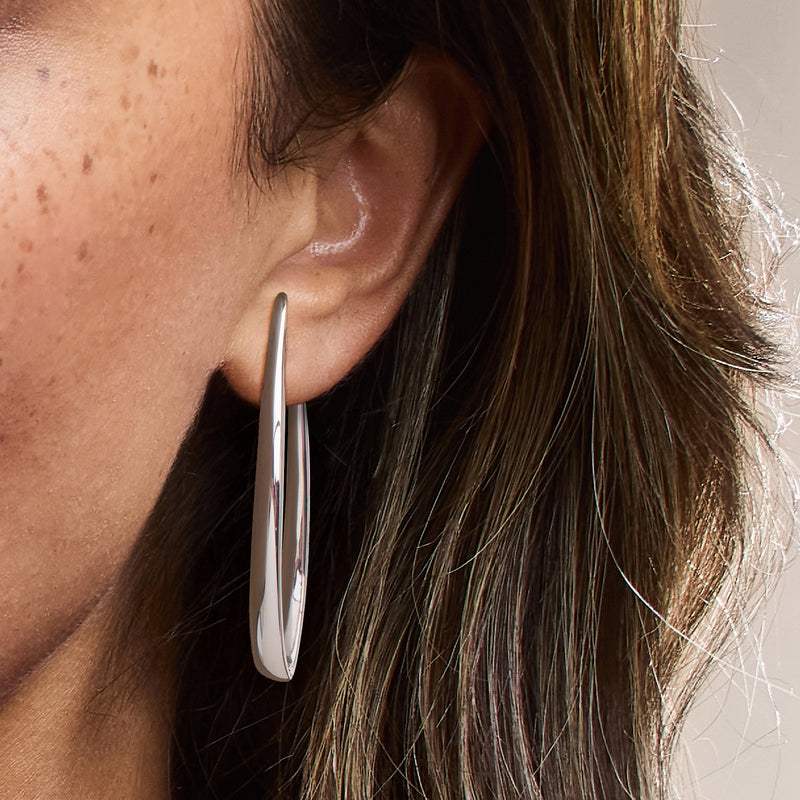 Sterling silver hoop earring on ear, smooth polished oval design