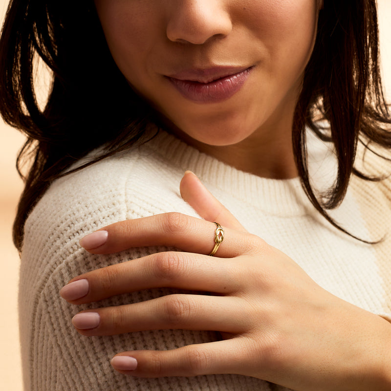 Yellow gold knot ring on hand, twisted knot detail on polished band