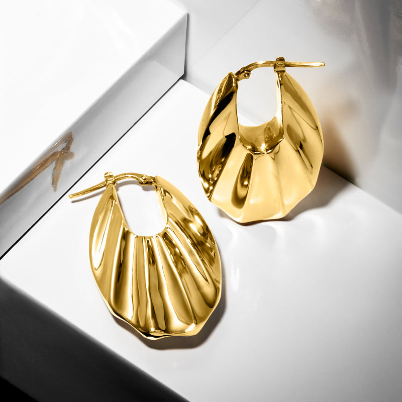 Yellow gold ribbed hoop earrings shown from a side angle, hinged clasp