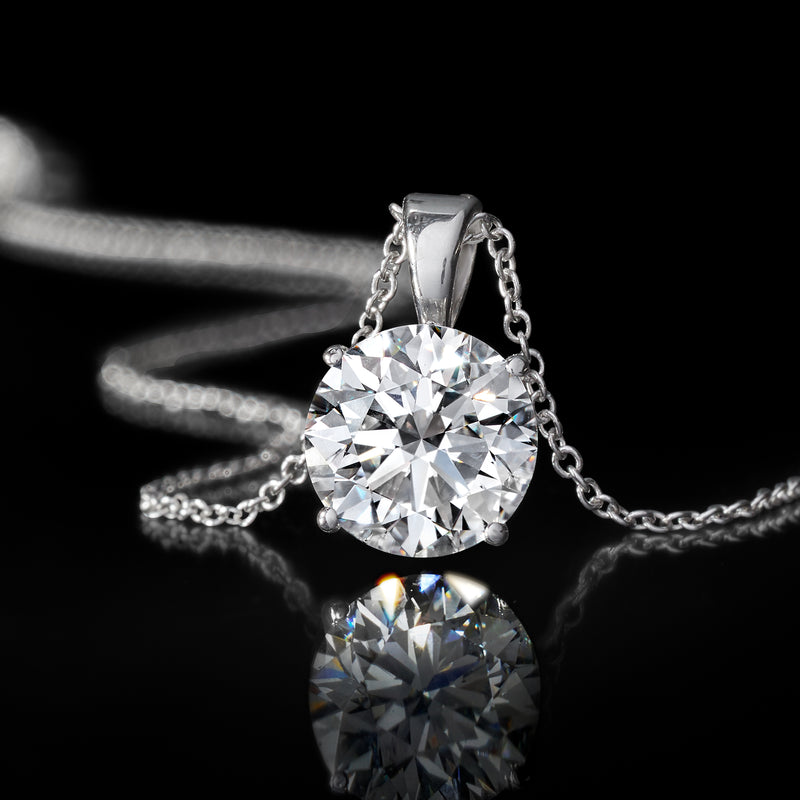 Close-up round diamond solitaire set in prongs on a white-gold necklace chain