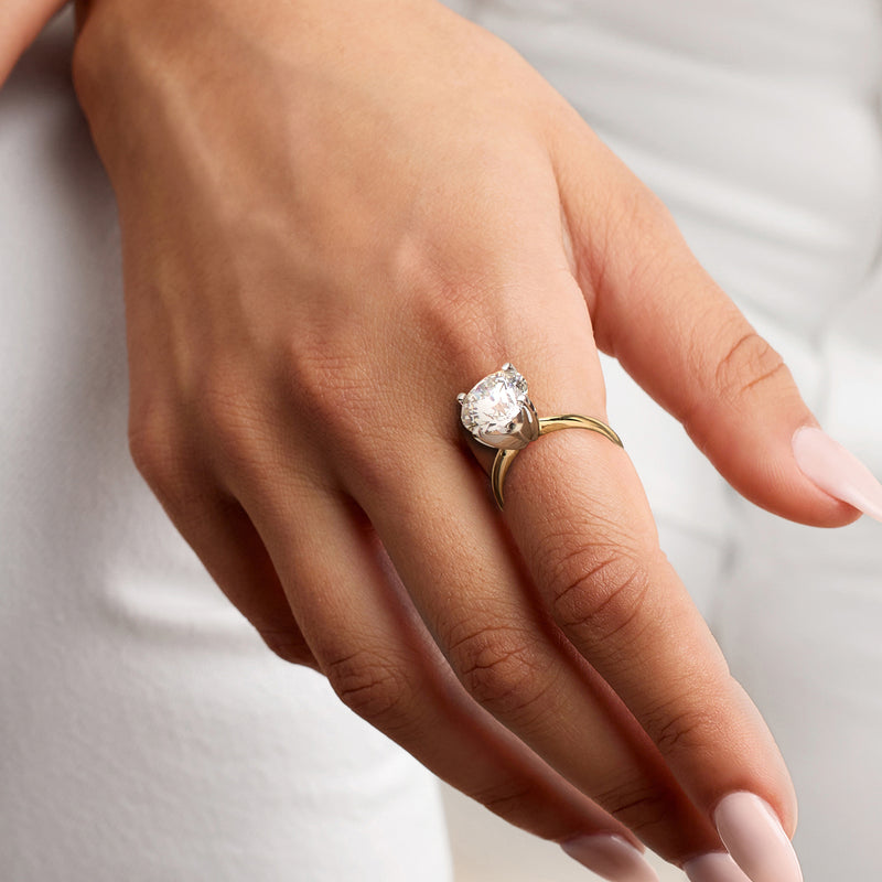 14kt yellow gold solitaire diamond ring on hand with round center stone and four prongs