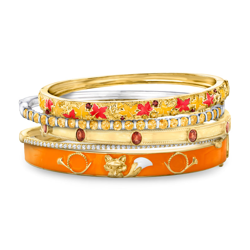 Five two-tone gold and silver bangle bracelets with orange enamel, crystals, and charms