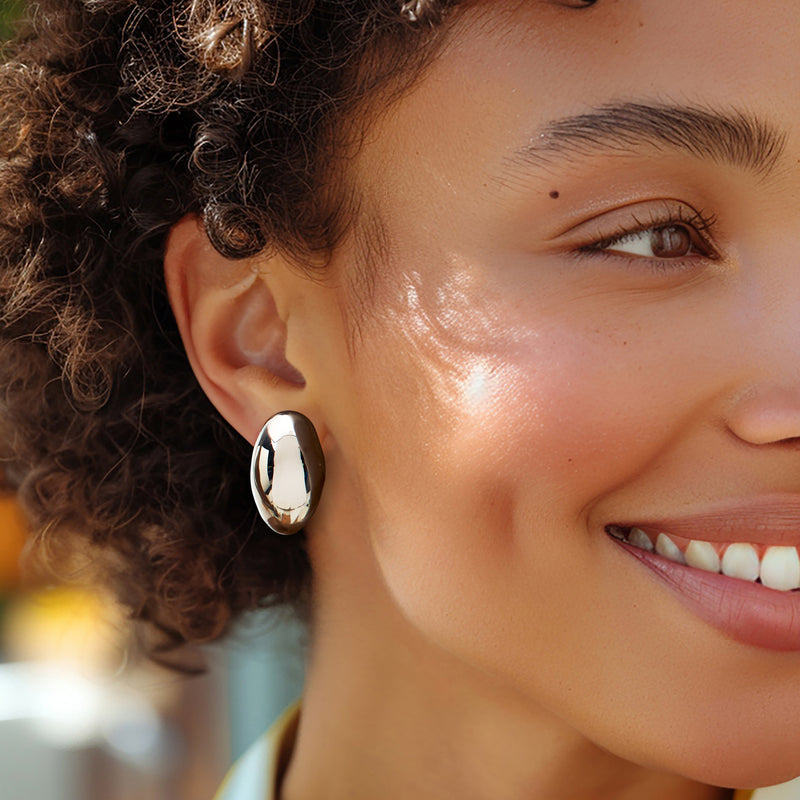 Polished oval dome sterling silver earrings on ear, close-up