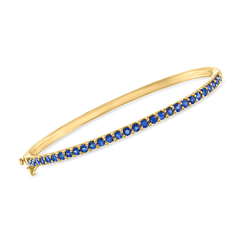 Gold-tone bangle with blue oval gems and a row of small round crystals