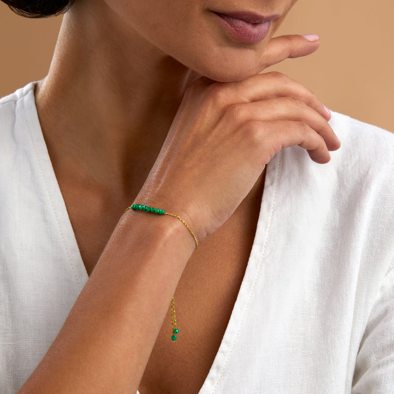 Emerald green bead bolo bracelet on wrist with 14kt yellow gold chain