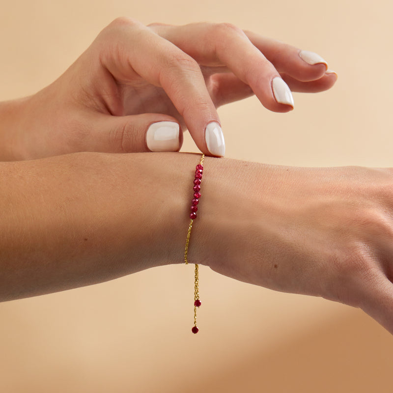 Ruby bead bolo bracelet in 14kt yellow gold worn on wrist with pink bead fringe